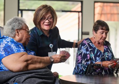 Caregiver and residents at the La Jolla Nursing and Rehab facility playing cards