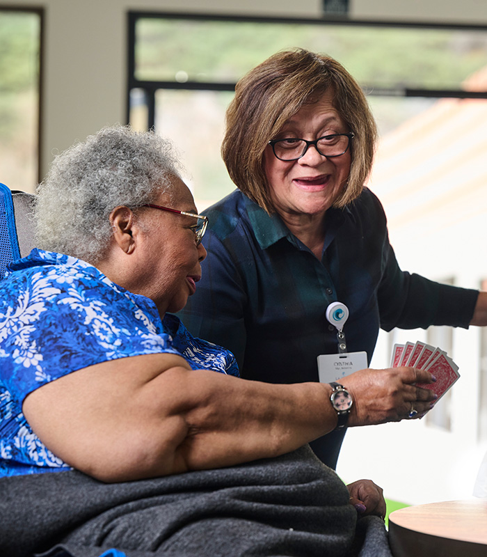 Caregiver and residents at the La Jolla Nursing and Rehab facility playing cards